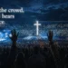 Large Christian worship gathering at night with a glowing cross as thousands raise their hands in prayer and praise.